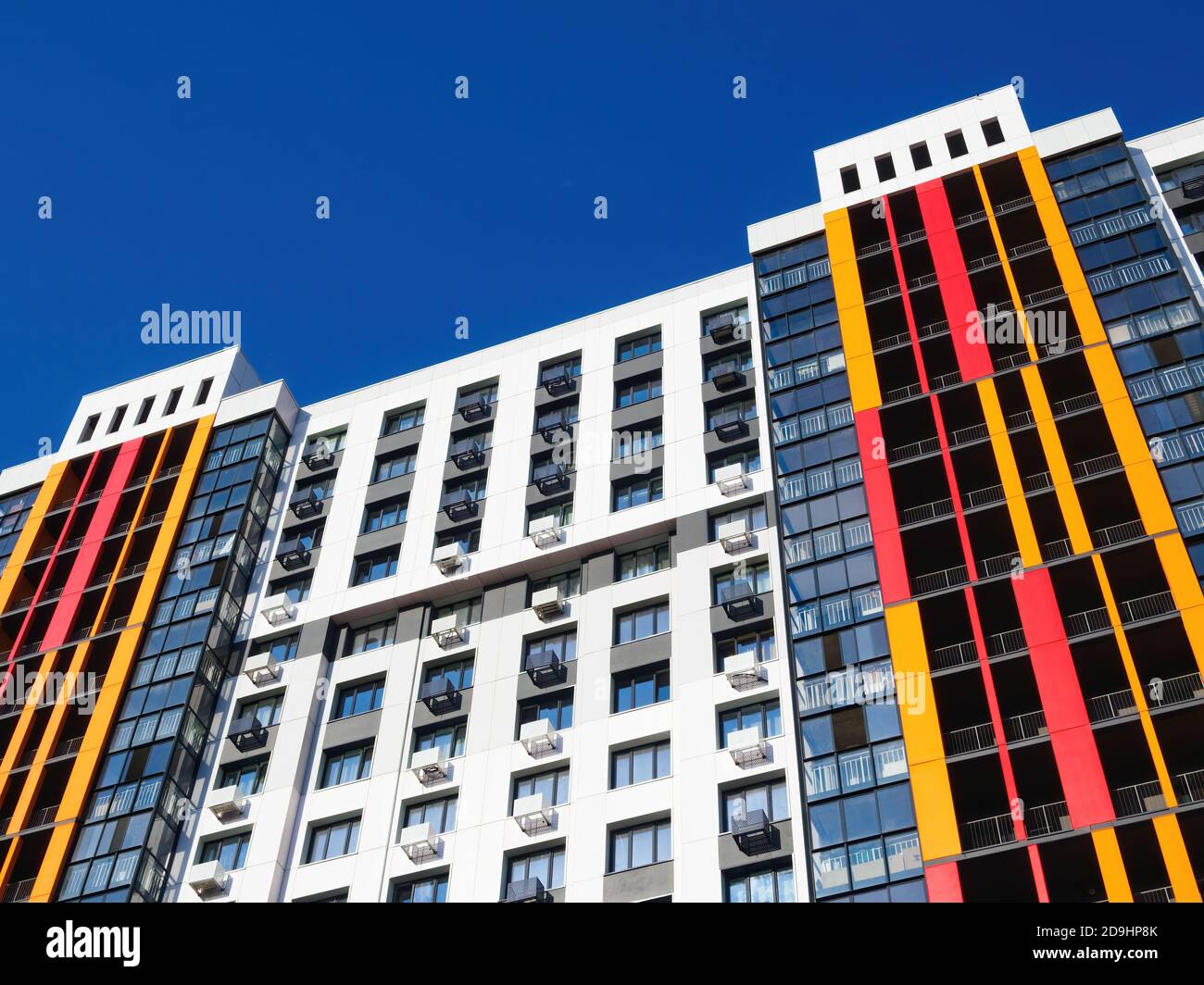 Façade de bâtiment moderne avec fenêtres, balcons et boîtes de climatisation sur fond bleu ciel. Banque D'Images