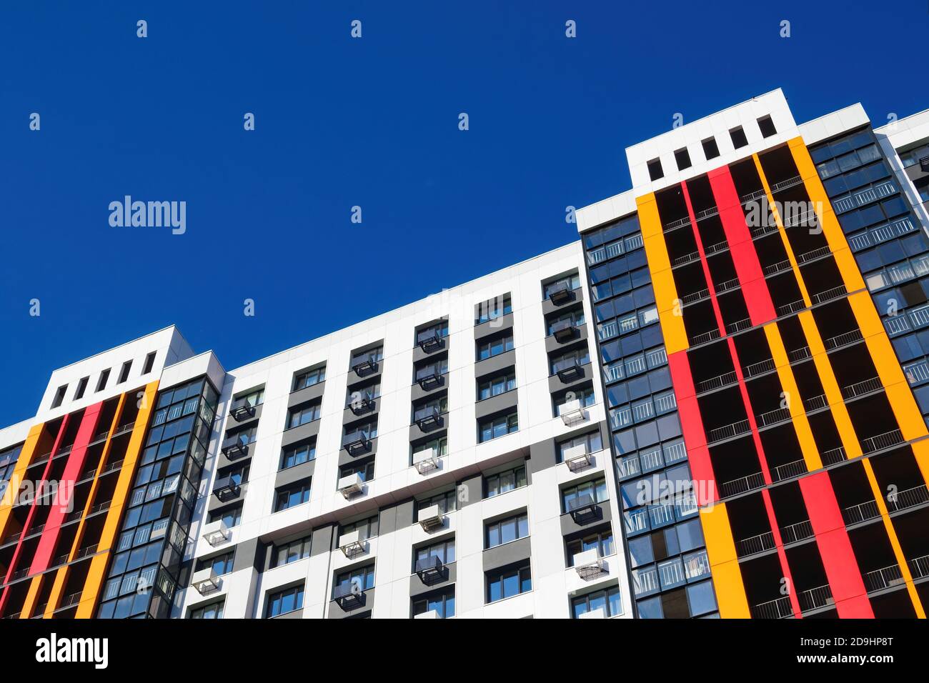 Façade de bâtiment moderne avec fenêtres, balcons et boîtes de climatisation sur ciel bleu. Copier l'espace, afficher selon un angle. Banque D'Images