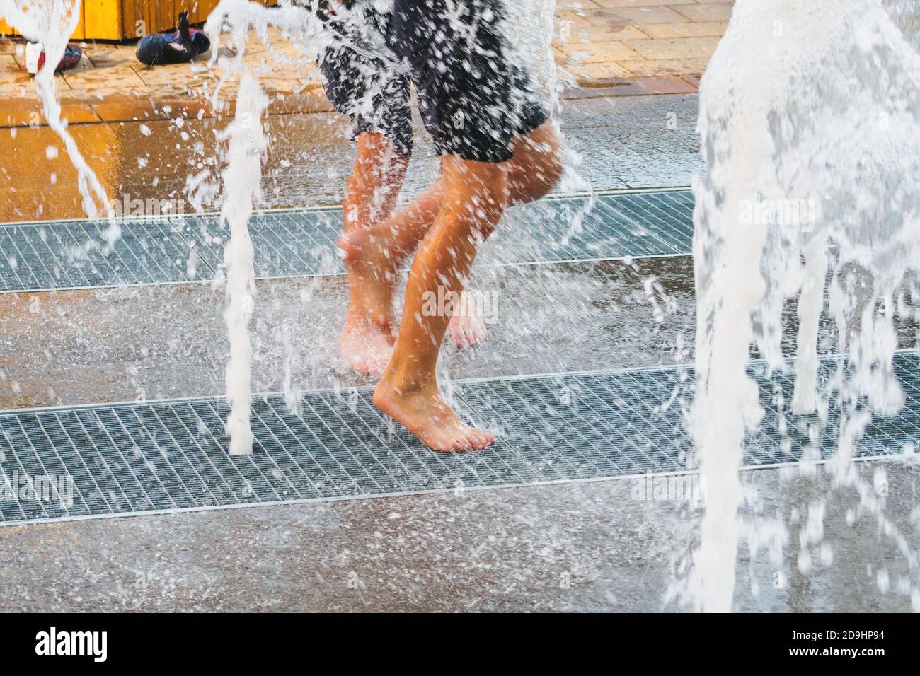 Jambes de course brouillées à travers la fontaine d'eau du sol, concept de style de vie, temps heureux d'enfance. Banque D'Images