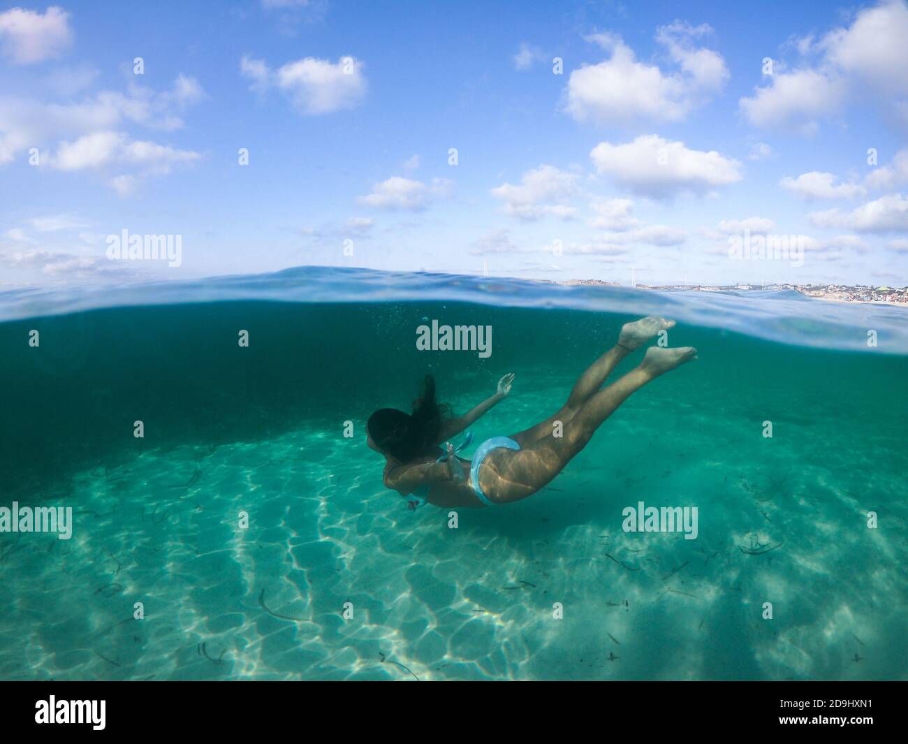 Femme plongée dans la mer. Affichage au niveau de l'eau, caméra submergée à 50 %, photo avec dôme sous-marin. Banque D'Images