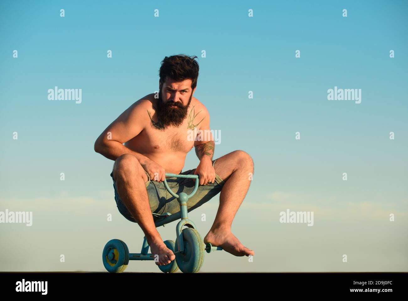Drôle d'homme sur un vélo. Un homme fou et émotif sur un vélo pour enfants. Un fou qui fait du vélo. Banque D'Images