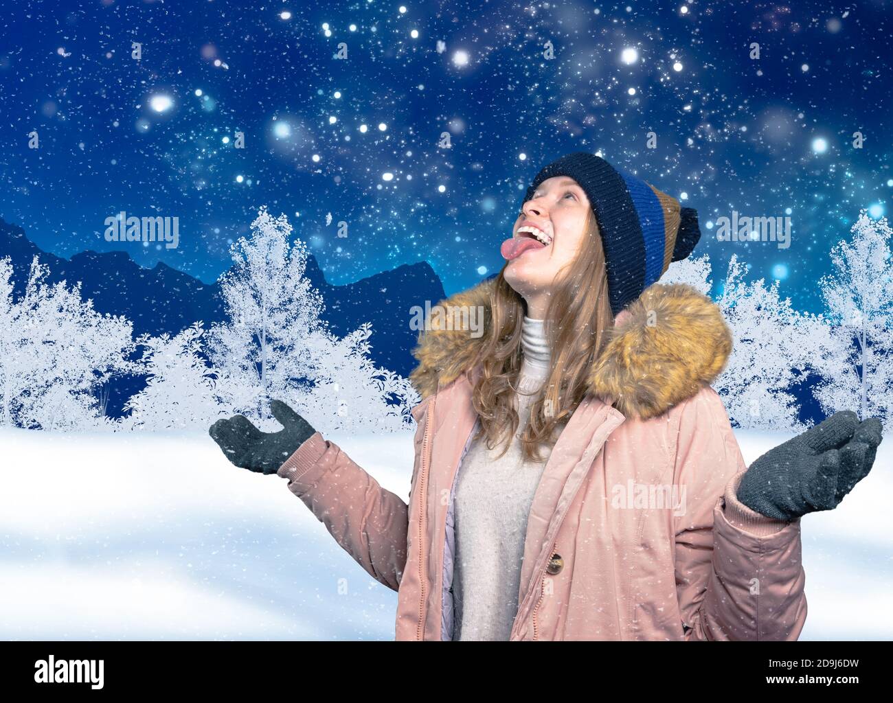 une jeune femme en paysage de wintry attrape des flocons de neige avec elle bouche Banque D'Images