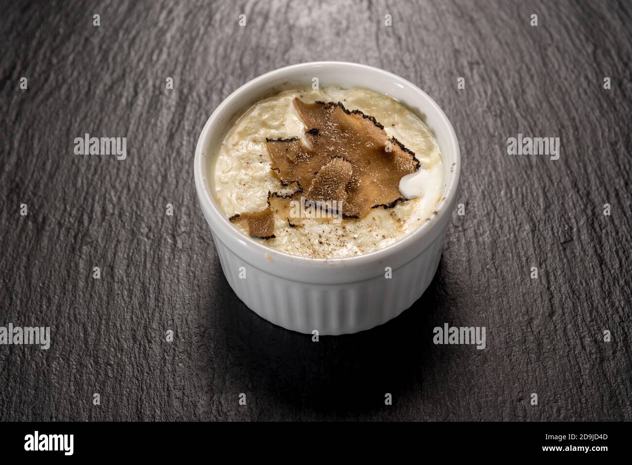 Fondue aux œufs et au fromage ​​fontina cuite avec une truffe en tranches de cocotte, sur une surface en pierre d'ardoise noire Banque D'Images