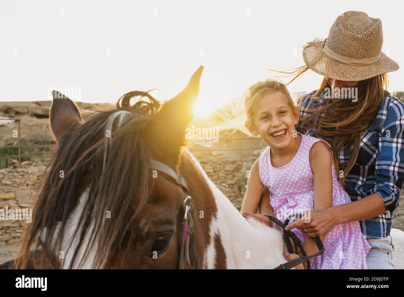 Bonne famille mère et fille ayant plaisir à faire du cheval à l'intérieur ranch Banque D'Images