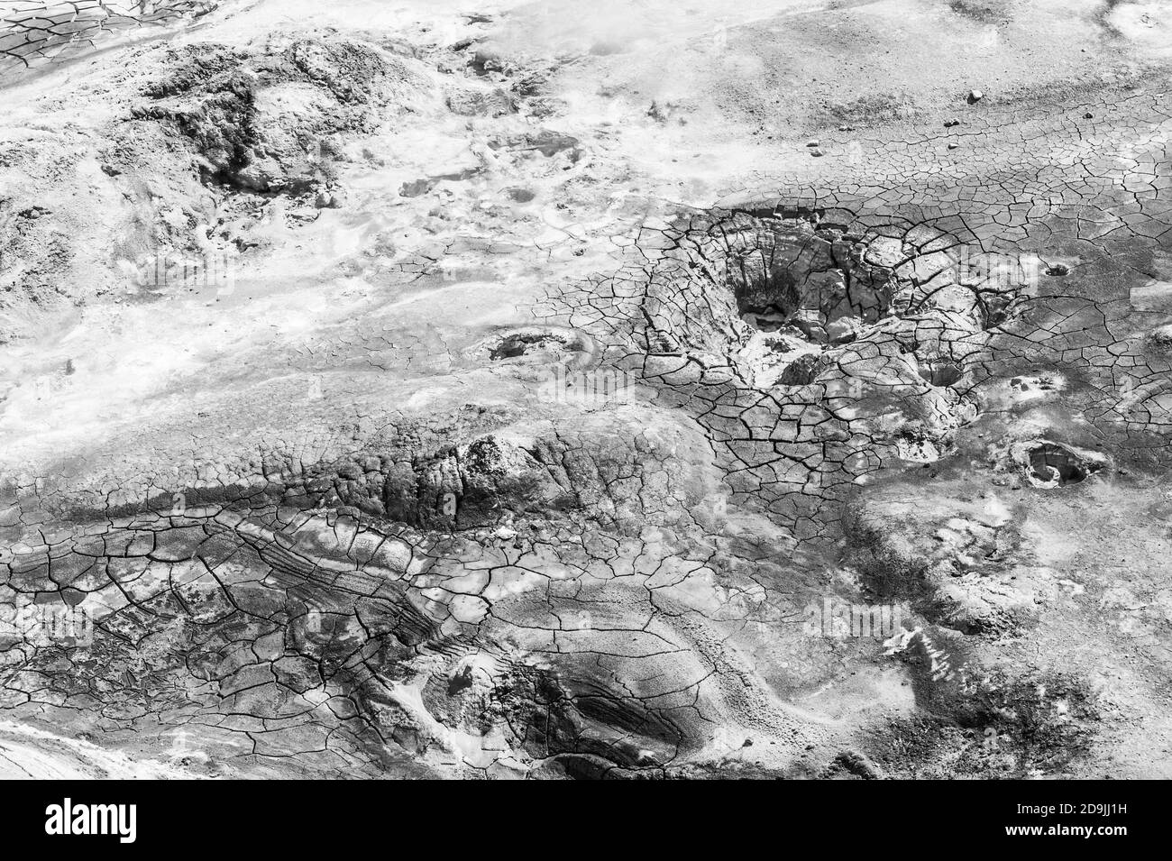 Mudpot dans la zone géothermique Hverir, Islande. La zone autour de la boue bouillante est fissurée. Monochrome Banque D'Images