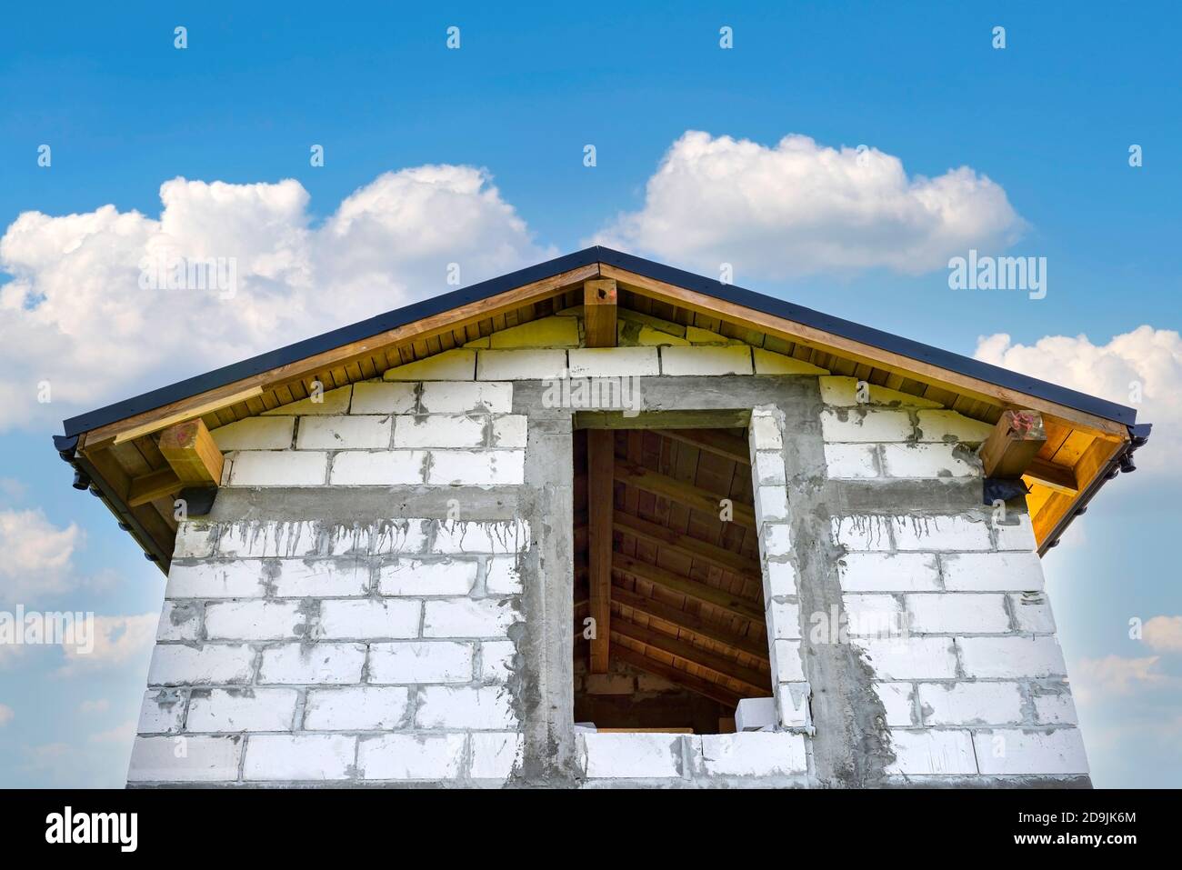 Construction d'une petite maison en brique blanche, toit ouvrant visible avec système d'embarquement et de caniveaux. Banque D'Images