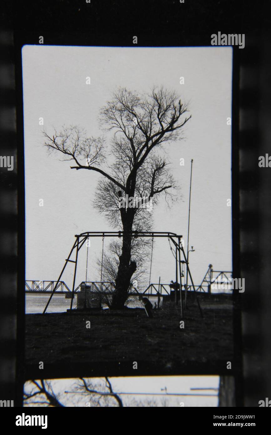 Belle photographie en noir et blanc vintage des années 1970 d'une balançoire sur le terrain de jeu. Banque D'Images