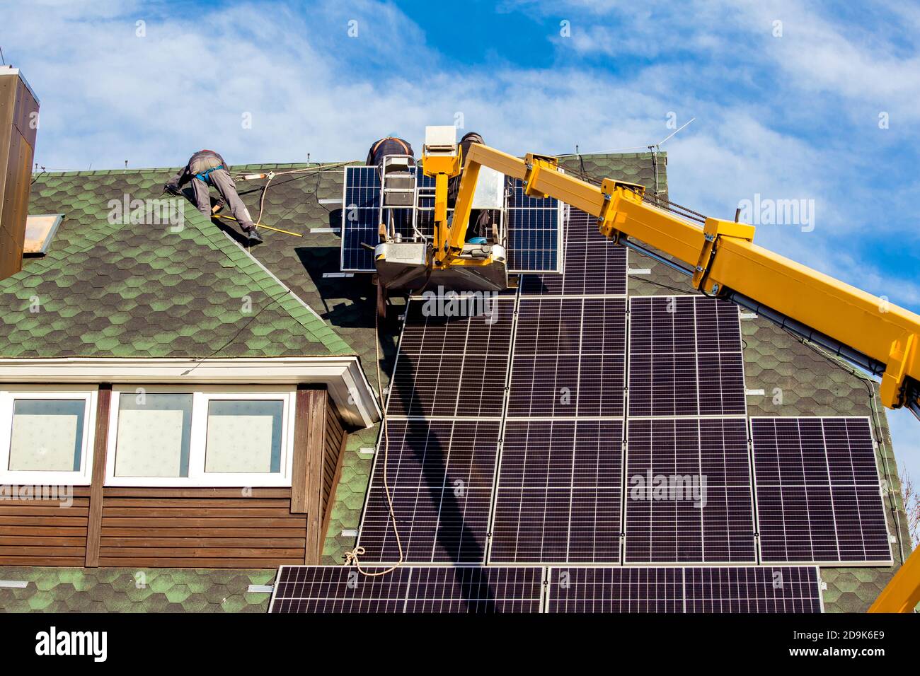 Les travailleurs qui installent des panneaux solaires sur le toit hexagonal de la maison privée se sont sentis le jour ensoleillé, ciel bleu. La vie réelle. Centrale électrique domestique. Banque D'Images