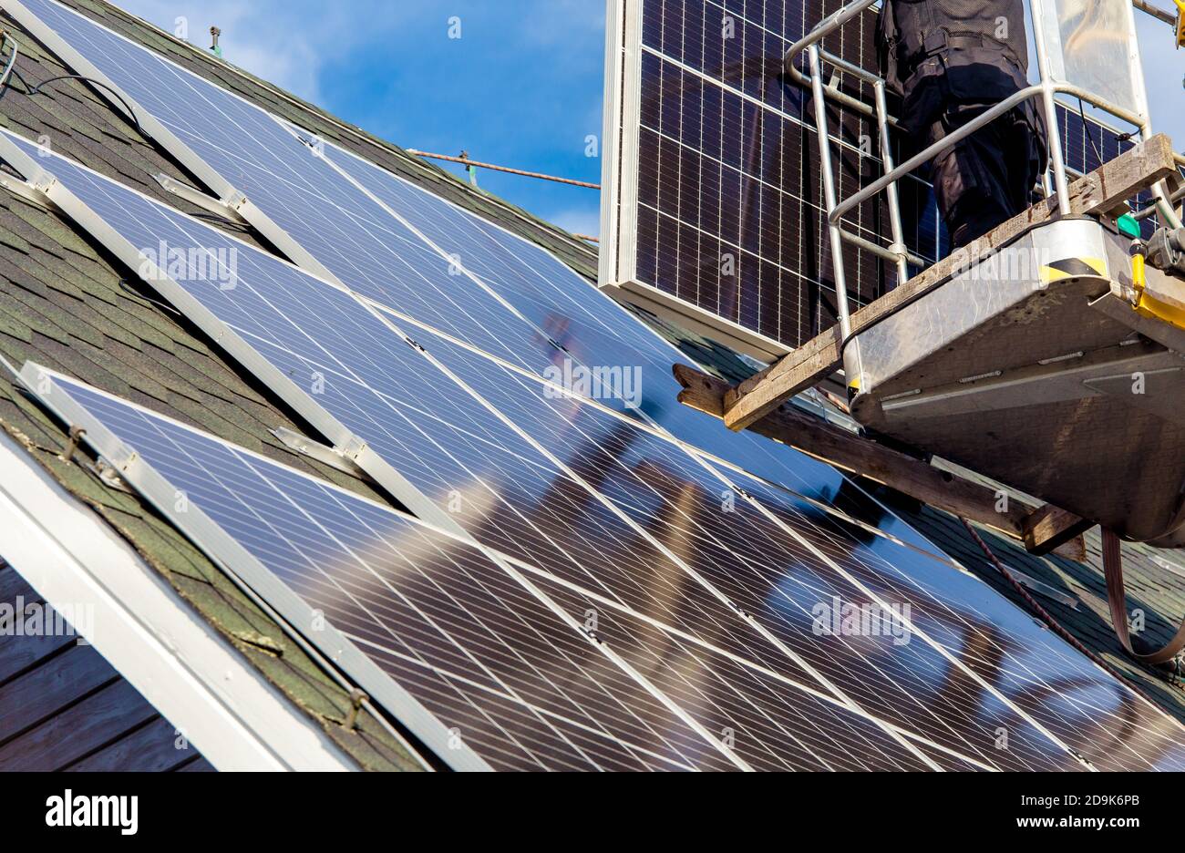 Les travailleurs qui installent des panneaux solaires sur le toit hexagonal de la maison privée se sont sentis le jour ensoleillé, ciel bleu. La vie réelle. Centrale électrique domestique. Banque D'Images