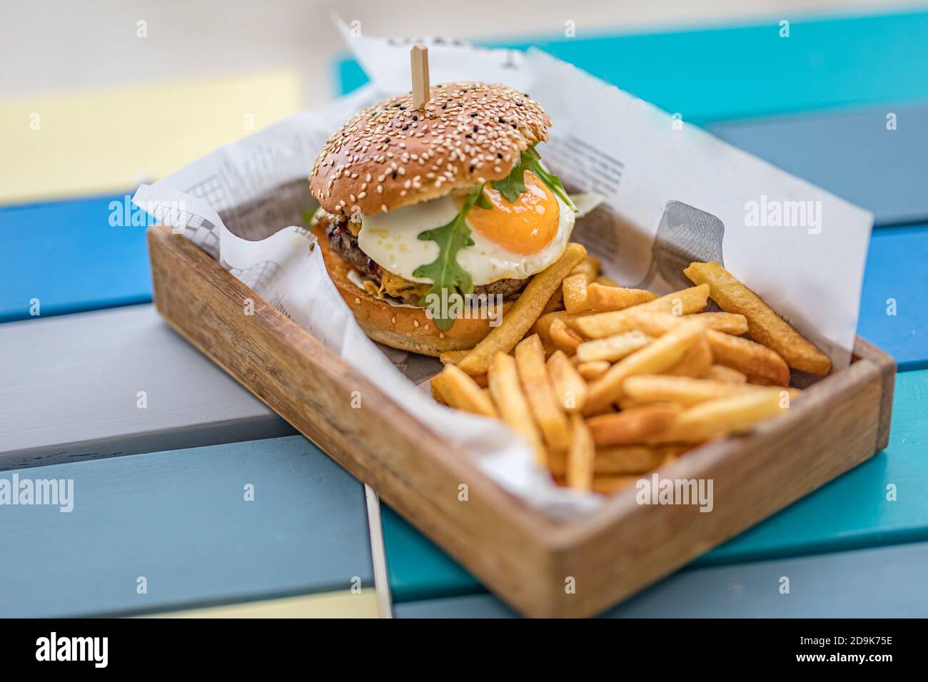 Hamburger et frites. Hamburger géant aux frites dans une assiette en bois. Hamburger gastronomique fait maison sur le plateau de table du restaurant extérieur Banque D'Images Hamburger et frites. Hamburger géant aux frites dans une assiette en bois. Hamburger gastronomique fait maison sur le plateau de table du restaurant extérieur Banque D'Images