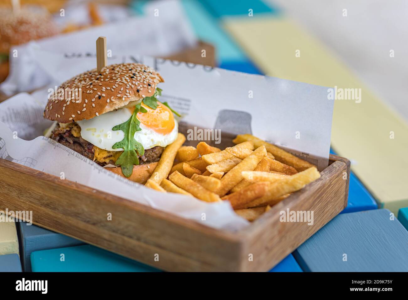 Hamburger et frites. Hamburger géant aux frites dans une assiette en bois. Hamburger gastronomique fait maison sur le plateau de table du restaurant extérieur Banque D'Images Hamburger et frites. Hamburger géant aux frites dans une assiette en bois. Hamburger gastronomique fait maison sur le plateau de table du restaurant extérieur Banque D'Images