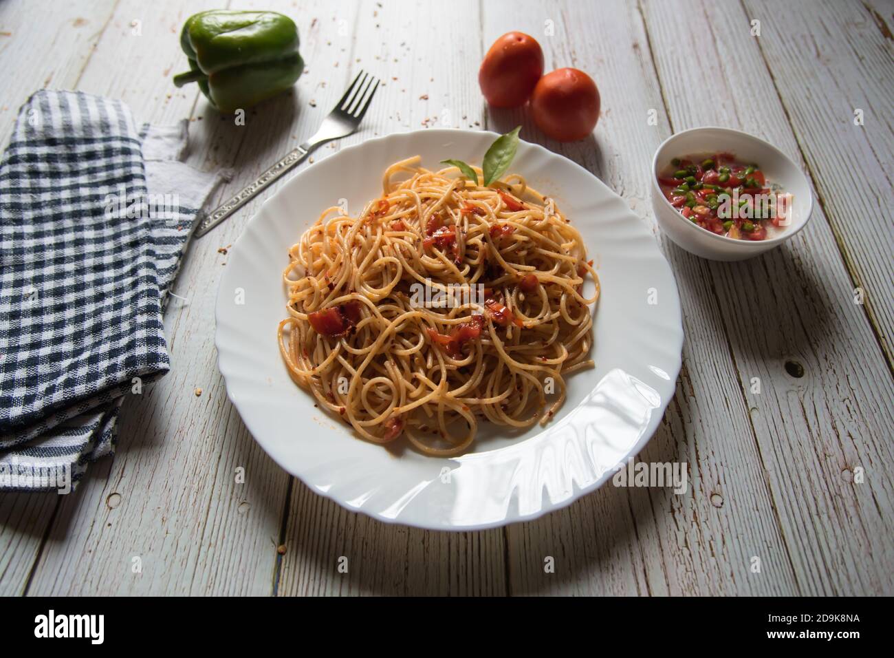 Gros plan de délicieux ingrédients alimentaires pâtes spaghetti fines italiennes dans une assiette avec condiments Banque D'Images