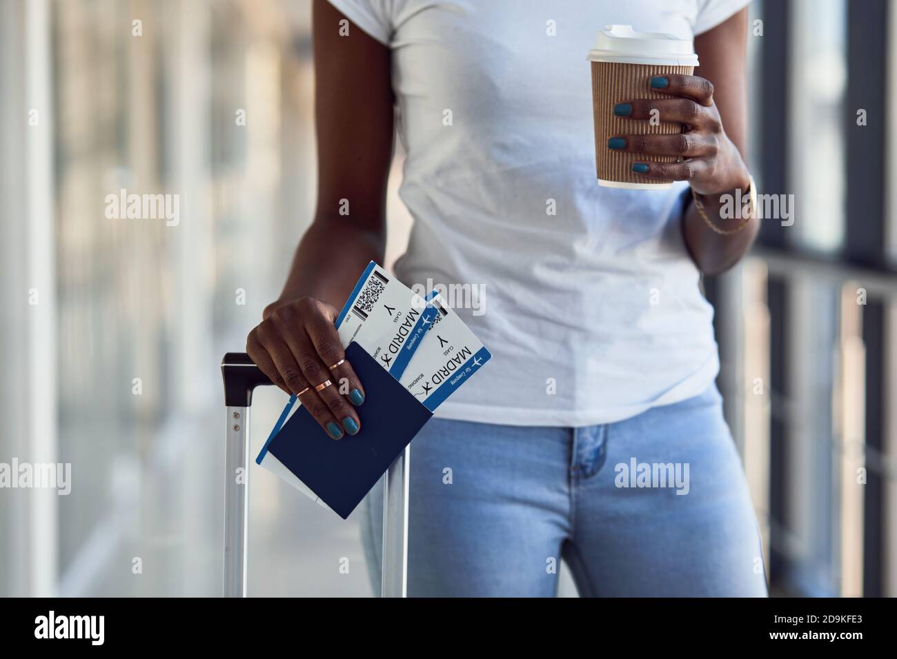 Une jeune femme afro-américaine en tenue décontractée est présente aéroport avec billets et boisson Banque D'Images