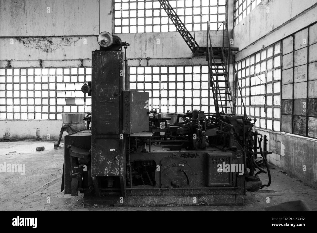 Prise de vue en niveaux de gris d'une usine industrielle dans un ancien atelier avec fenêtres en verre carrées Banque D'Images