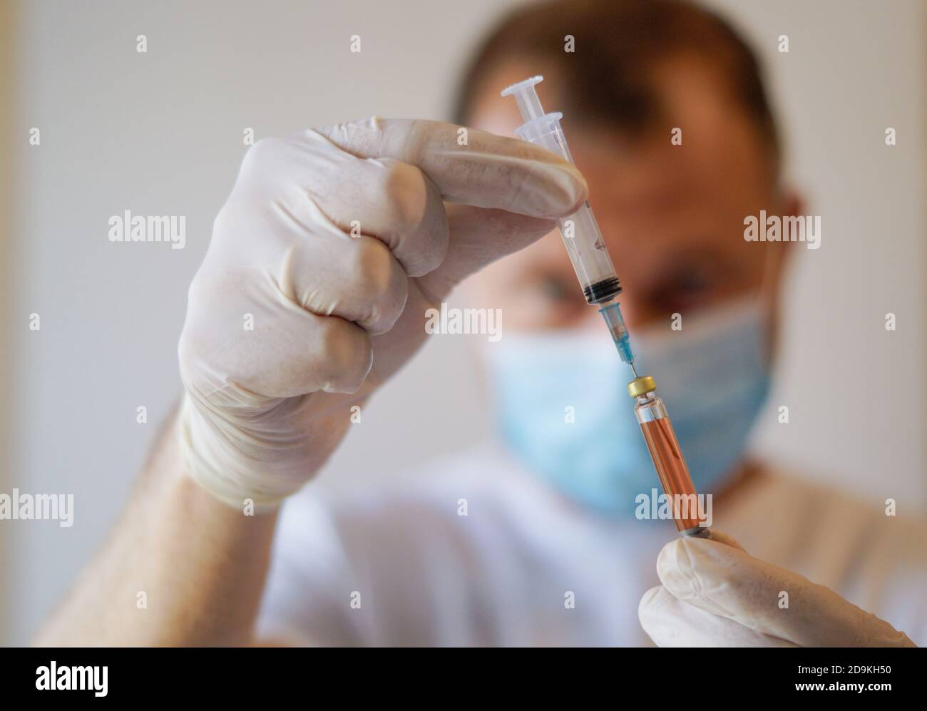 Gros plan d'un travailleur médical non reconnaissable portant un masque de protection et Gants contenant une seringue avec le vaccin Covid-19 Banque D'Images
