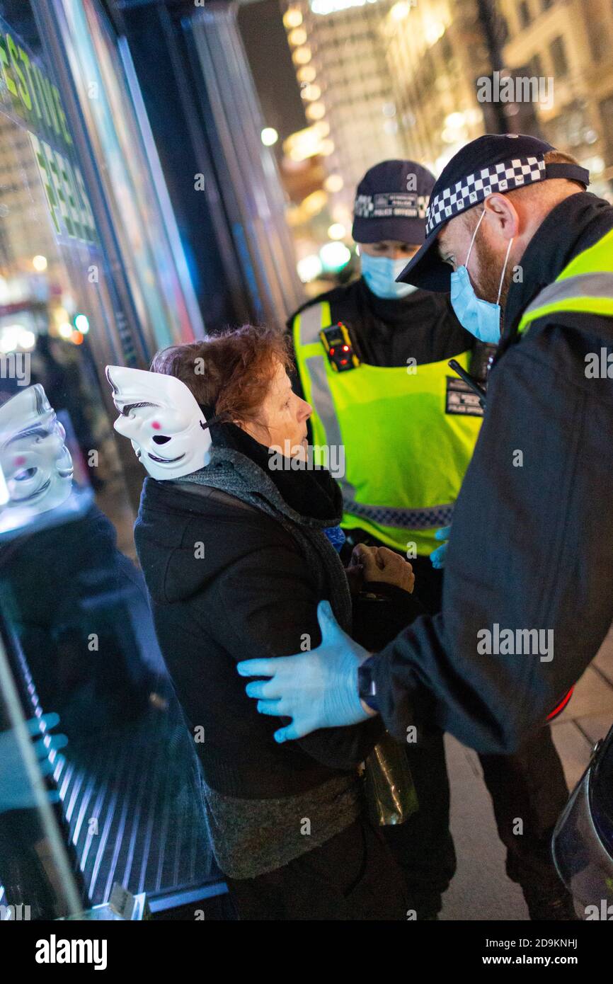 Une femme est détenue par la police au cours de la marche million Mask à laquelle de nombreux sceptiques du confinement ont assisté, Londres, 5 novembre 2020 Banque D'Images