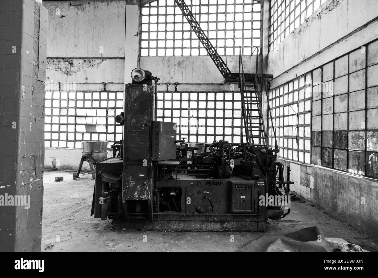 Prise de vue en niveaux de gris d'une usine industrielle dans un ancien atelier avec fenêtres en verre carrées Banque D'Images