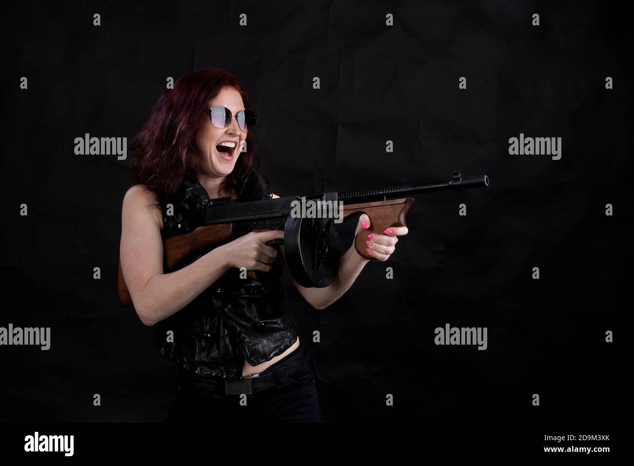 Belle femme vêtue d'une veste noire avec un studio d'armes à feu portrait Banque D'Images