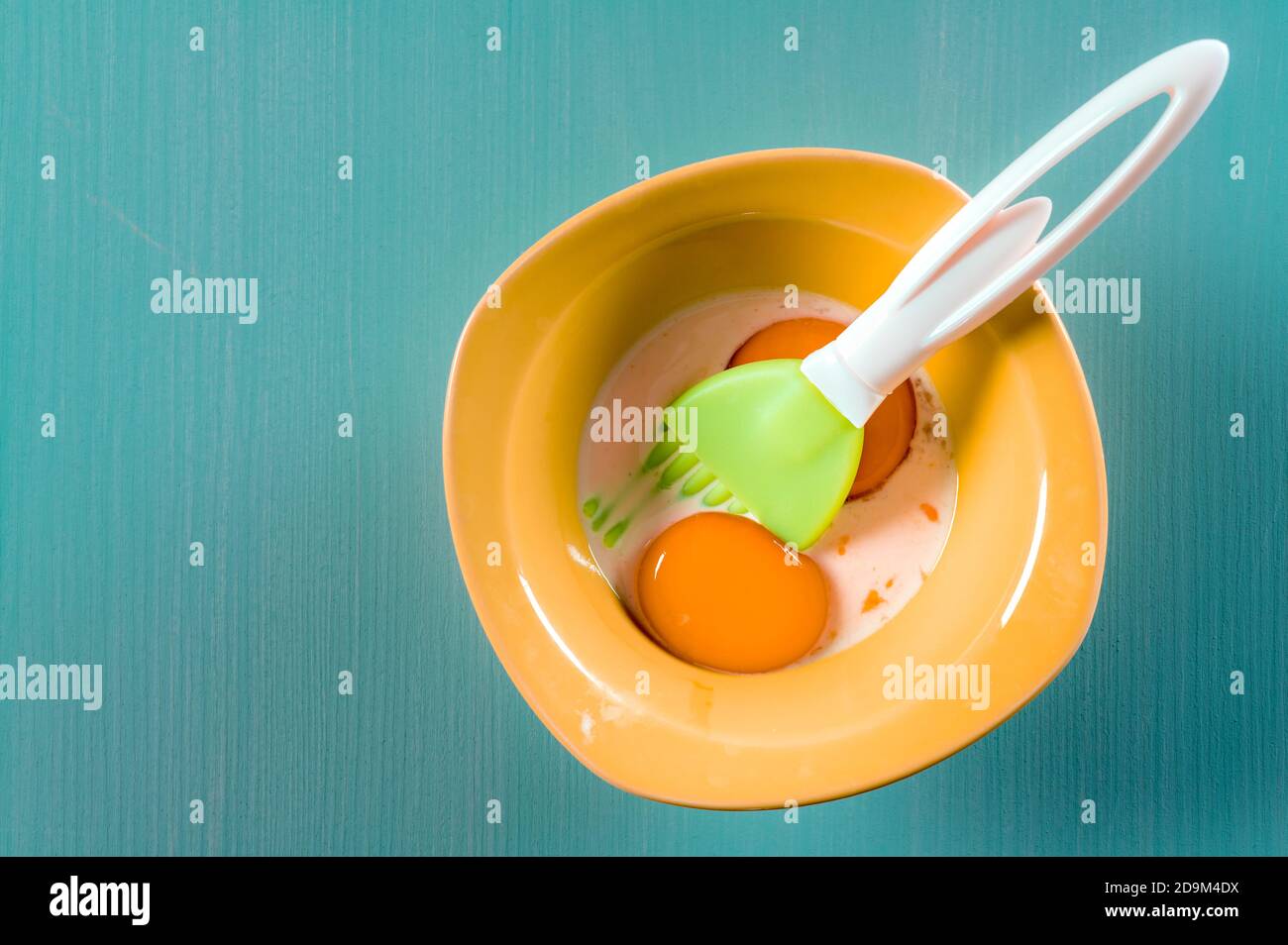 Vue de dessus du jaune d'œuf et du lait dans un bol avec une brosse à pâtisserie Banque D'Images