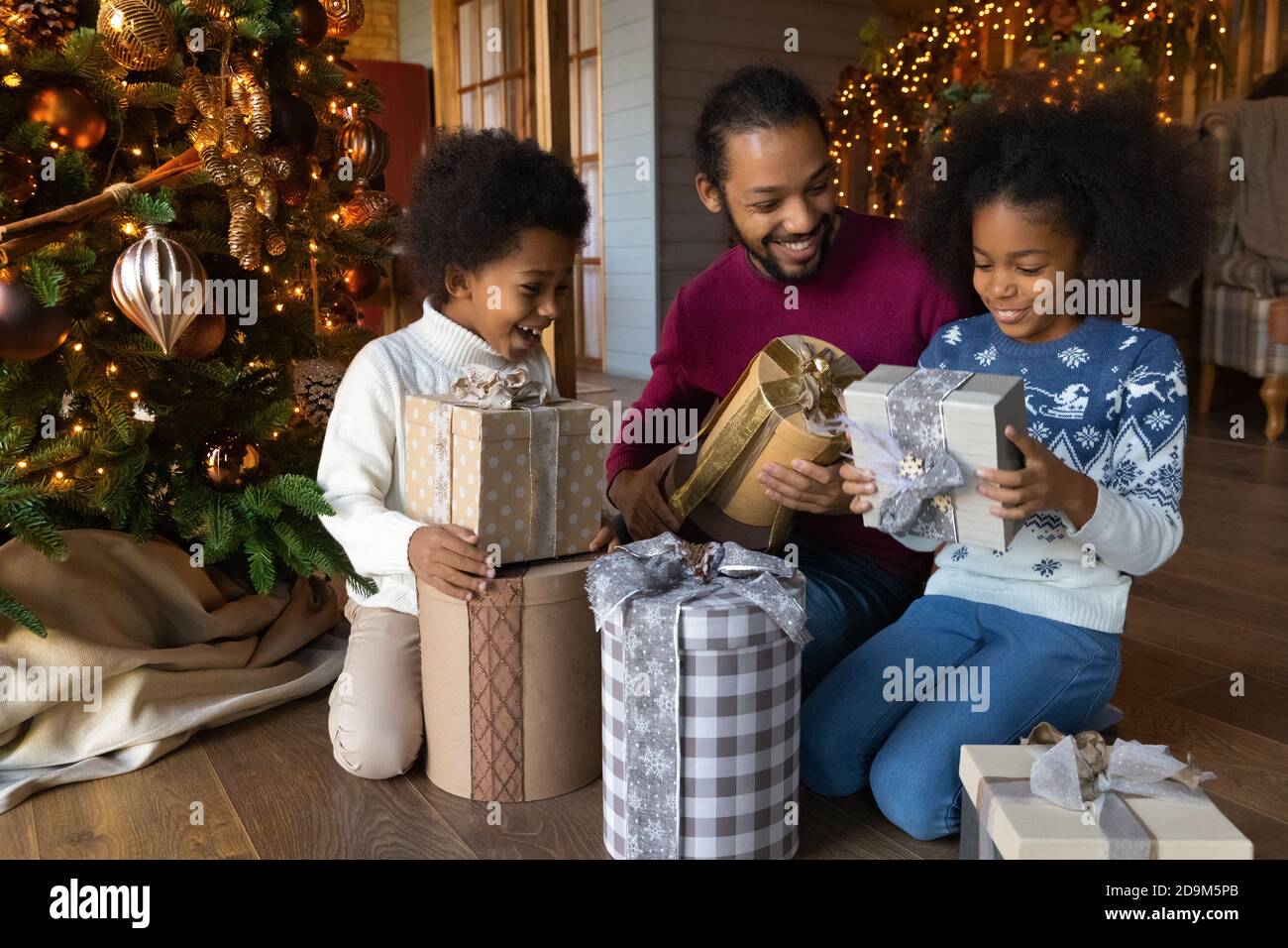 Gros plan la famille afro-américaine surjoyeuse déballant des cadeaux de Noël Banque D'Images