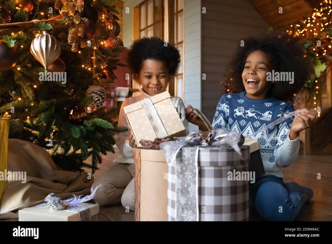 Gros plan les enfants afro-américains surjoyeux déballant des cadeaux de Noël Banque D'Images