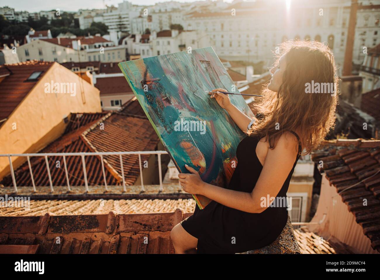 Femme peintre avec toile d'art abstrait travaillant sur le toit Banque D'Images