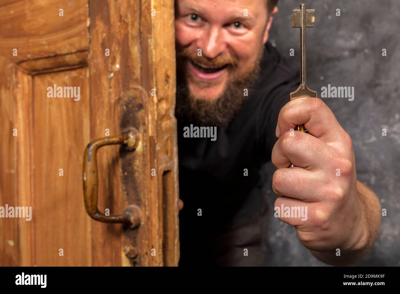 Homme barbu plein de joie avec la clé qui se déporte de la porte portrait de studio émotionnel Banque D'Images