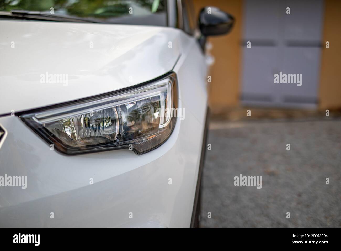 Voiture blanche avec lumières en bas, en face de la maison à l'allée. 4x4 et allée de gravier de maison méditerranéenne Banque D'Images