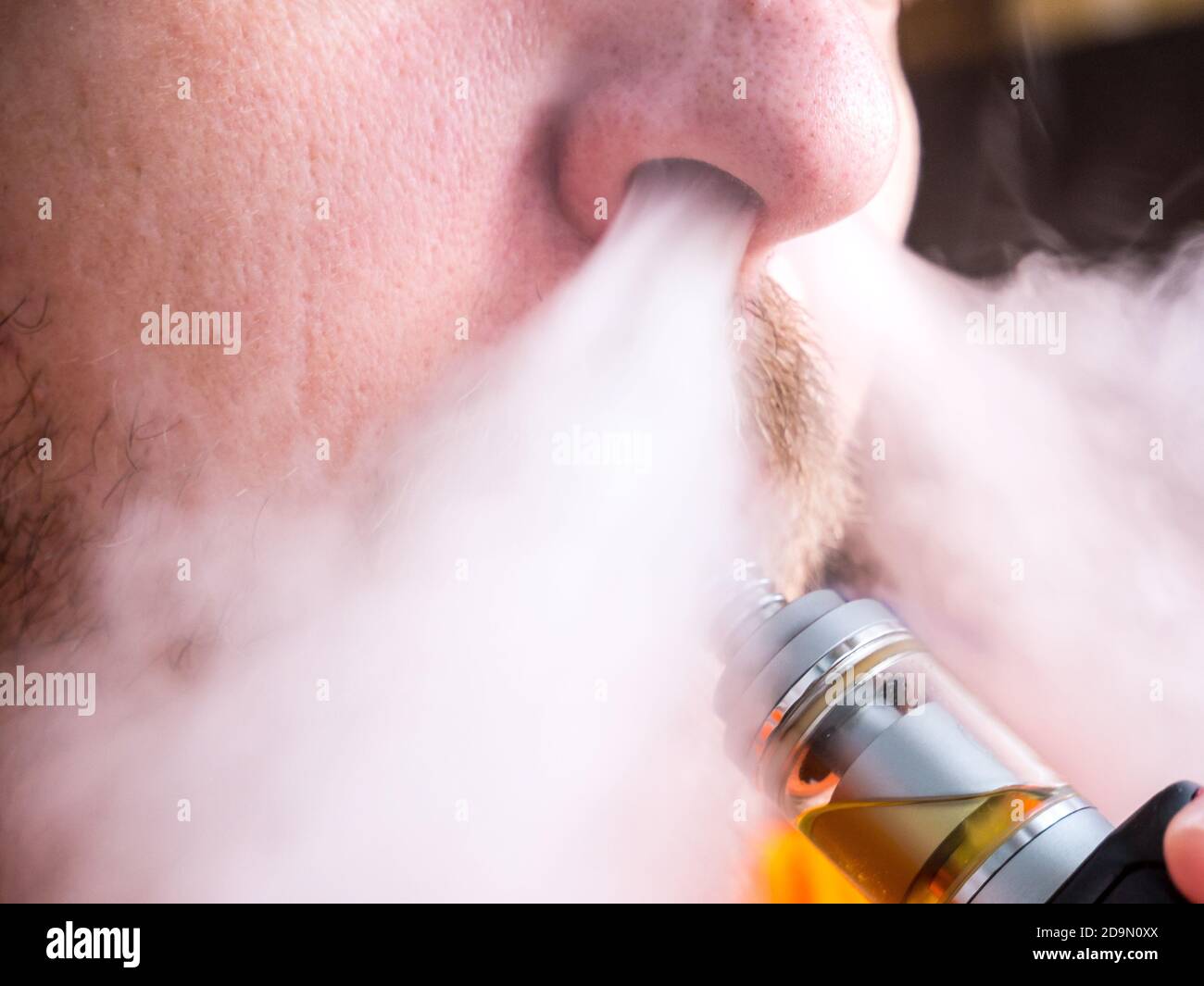 Gros plan de la bouche avec moustache à l'aide d'une cigarette électronique, en soufflant de la vapeur à travers le nez Banque D'Images