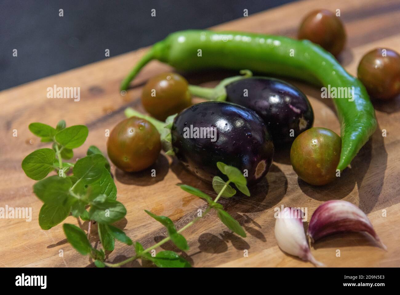 La récolte des aubergines et leur cuisine végétarienne: Une alimentation saine et durable de votre propre jardin. Légumes fraîchement récoltés sur une planche de bois. Banque D'Images