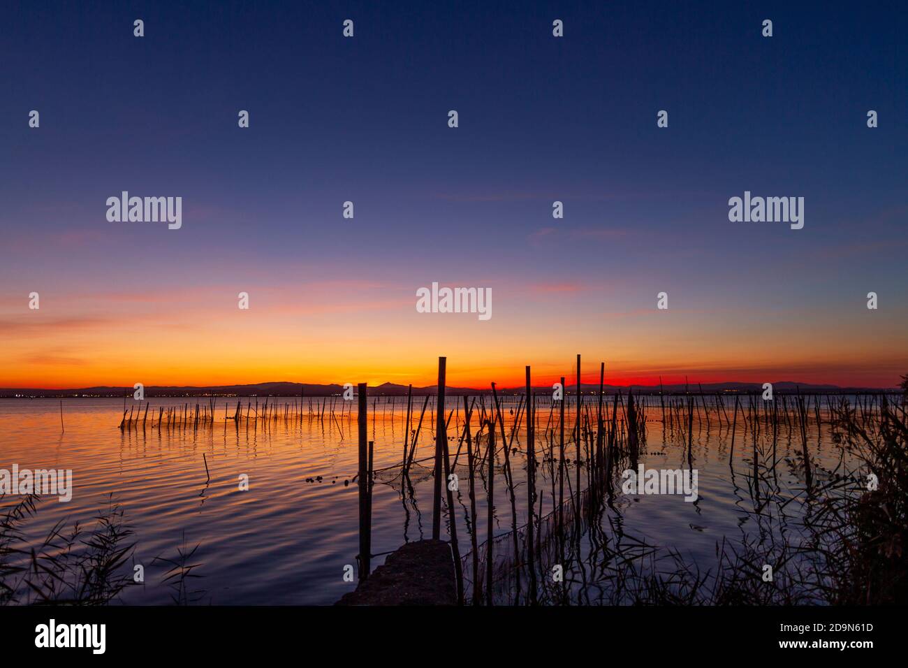 Magnifique coucher de soleil rom la Albufera à Valence (Espagne). Vous pouvez voir le matériel de pêche traditionnel utilisé par les pêcheurs locaux pour obtenir des anguilles et d'autres poissons. Banque D'Images