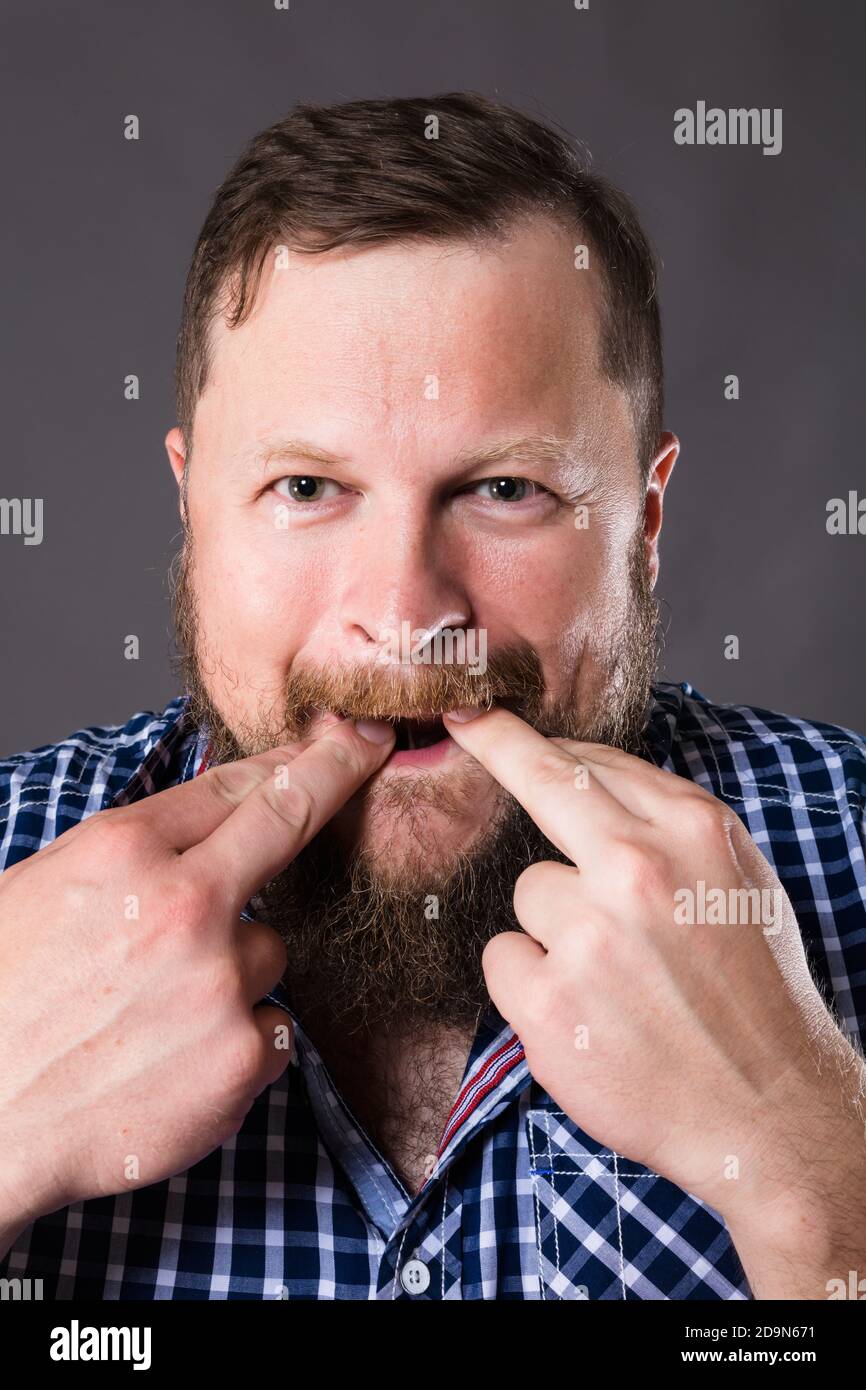 Joyeux barbu homme en chemise sifflant studio portrait sur gris arrière-plan Banque D'Images