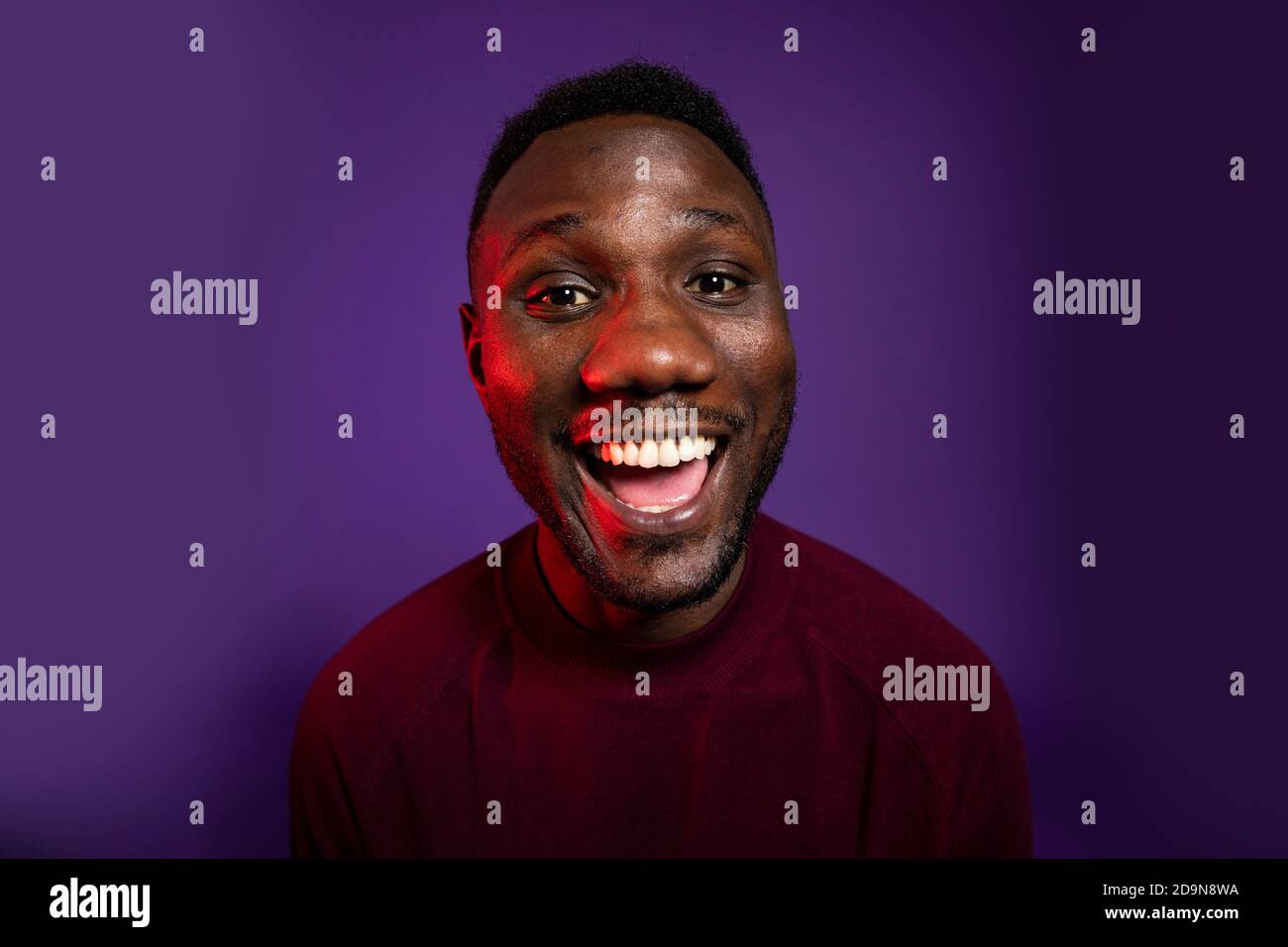 Homme africain souriant grand sourire avec la bouche ouverte à la caméra. Prise de vue moyenne. Arrière-plan isolé. Banque D'Images