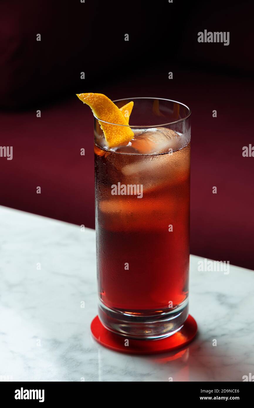 Cocktail Americano avec rotation orange sur une table en marbre. Canapé rouge comme arrière-plan Banque D'Images