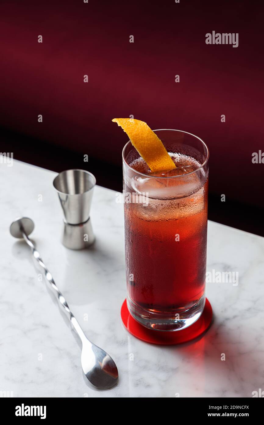 Cocktail Americano avec rotation orange sur une table en marbre. Canapé rouge comme arrière-plan Banque D'Images