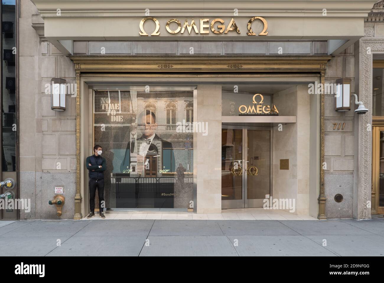 Une femme marche sur le trottoir d'une cinquième avenue vide devant un magasin fermé Salvatore Ferragamo. Banque D'Images