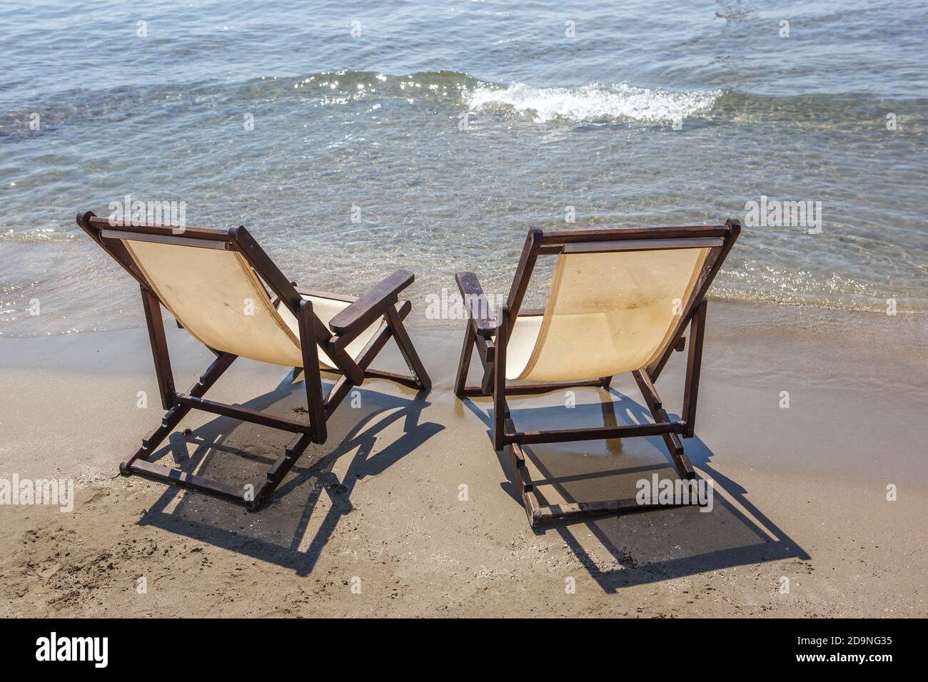 Deux chaises longues se trouvent sur la plage de sable, contre le mer Banque D'Images
