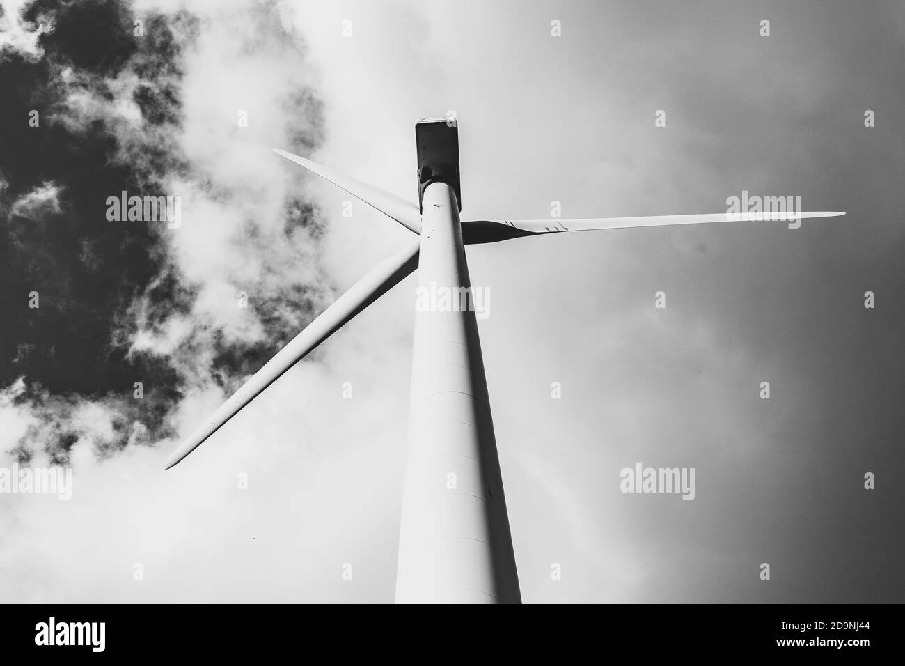 Prise de vue en niveaux de gris à faible angle d'un moulin à vent pour l'énergie électrique production avec un ciel nuageux derrière Banque D'Images