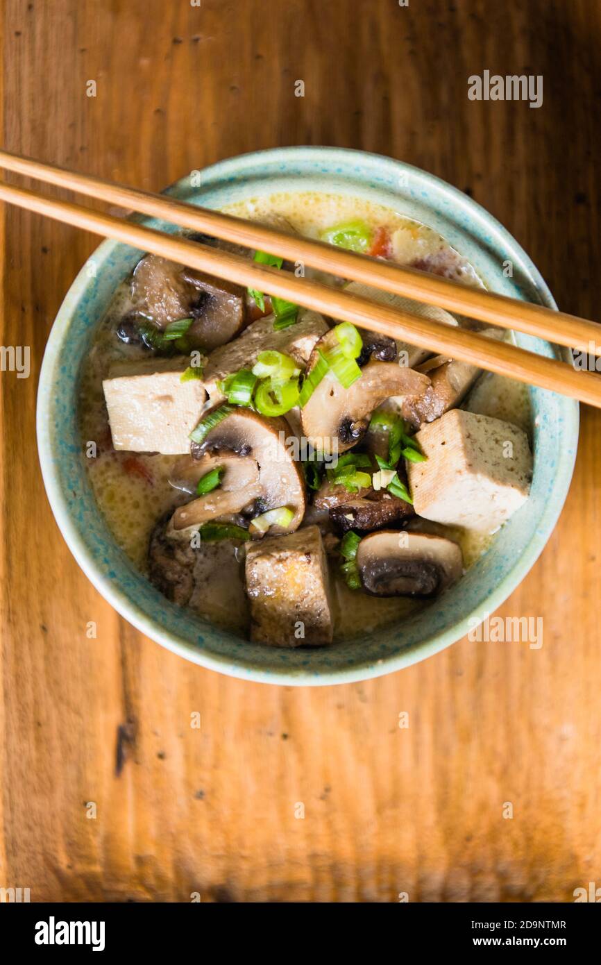 Soupe de tofu et de champignons dans un bol bleu avec baguettes de gros plan Banque D'Images