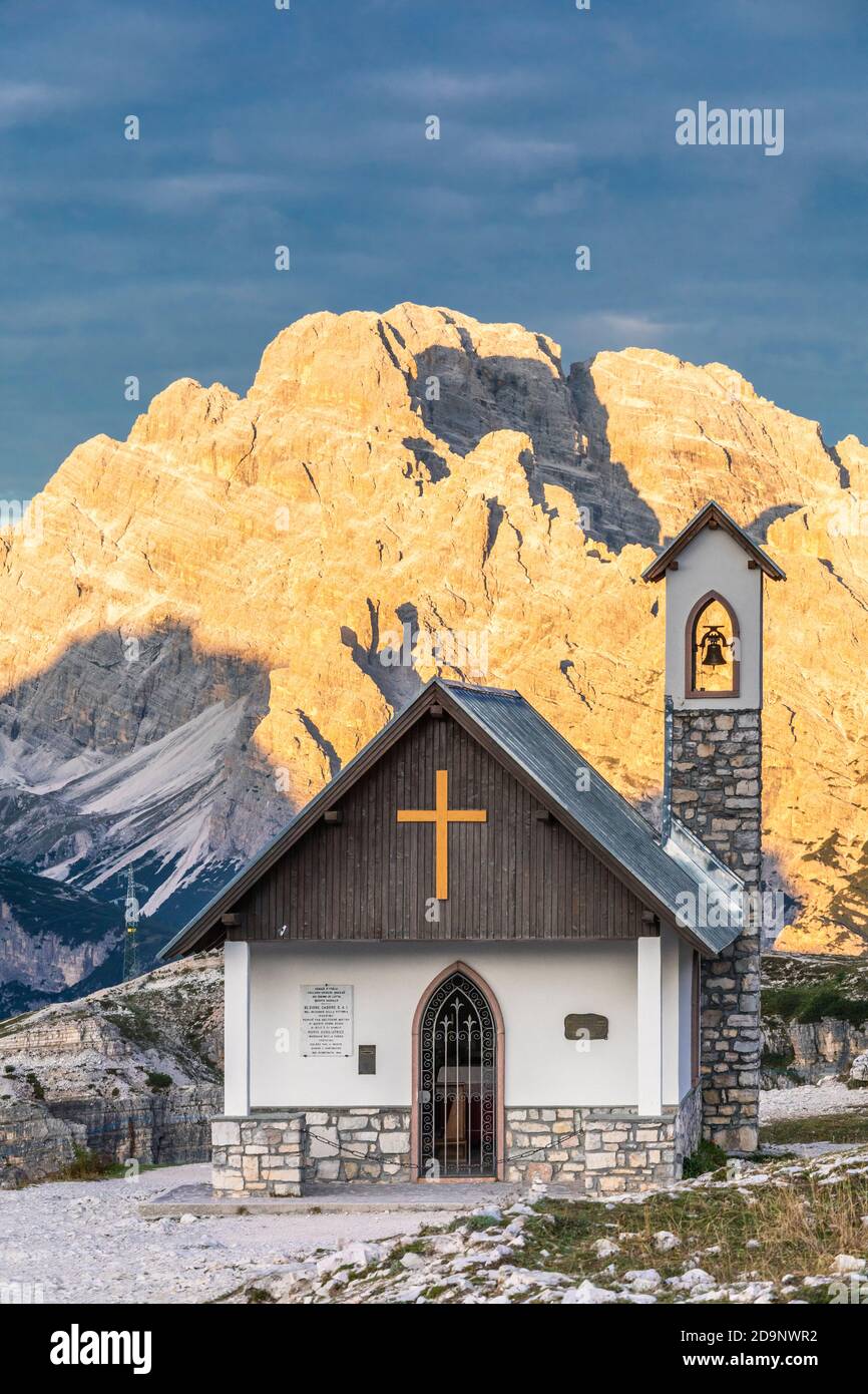Chapelle de l'Alpini (Cappella degli Alpini) au pied de la Tre Cime di Lavaredo, en arrière-plan le mont Cristallo embrassé par le soleil, les Dolomites, Auronzo di Cadore, province de Belluno, Vénétie, Italie, Europe Banque D'Images