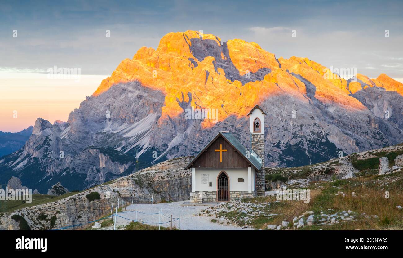 Chapelle de l'Alpini (Cappella degli Alpini) au pied de la Tre Cime di Lavaredo, en arrière-plan le mont Cristallo embrassé par le soleil, les Dolomites, Auronzo di Cadore, province de Belluno, Vénétie, Italie, Europe Banque D'Images