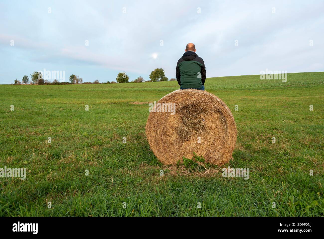 Homme assis sur une balle de paille sous le plein lune Banque D'Images
