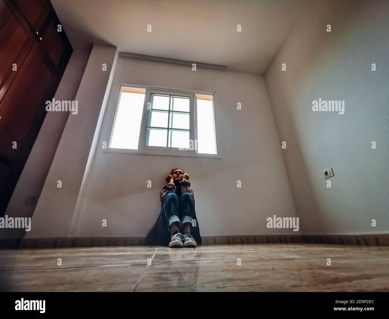 jeune femme assise malheureusement sur le sol dans un vide chambre Banque D'Images