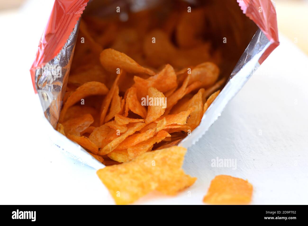 chips de pommes de terre couchés devant un sac de chips Fond blanc/ frites de pommes de terre salées/ en-cas malsain Banque D'Images