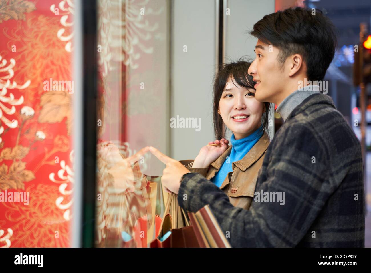 joyeux jeune couple asiatique regardant dans la fenêtre de magasin dans moderne ville Banque D'Images