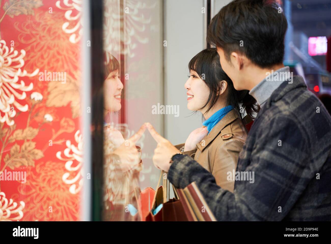 joyeux jeune couple asiatique regardant dans la fenêtre de magasin dans moderne ville Banque D'Images