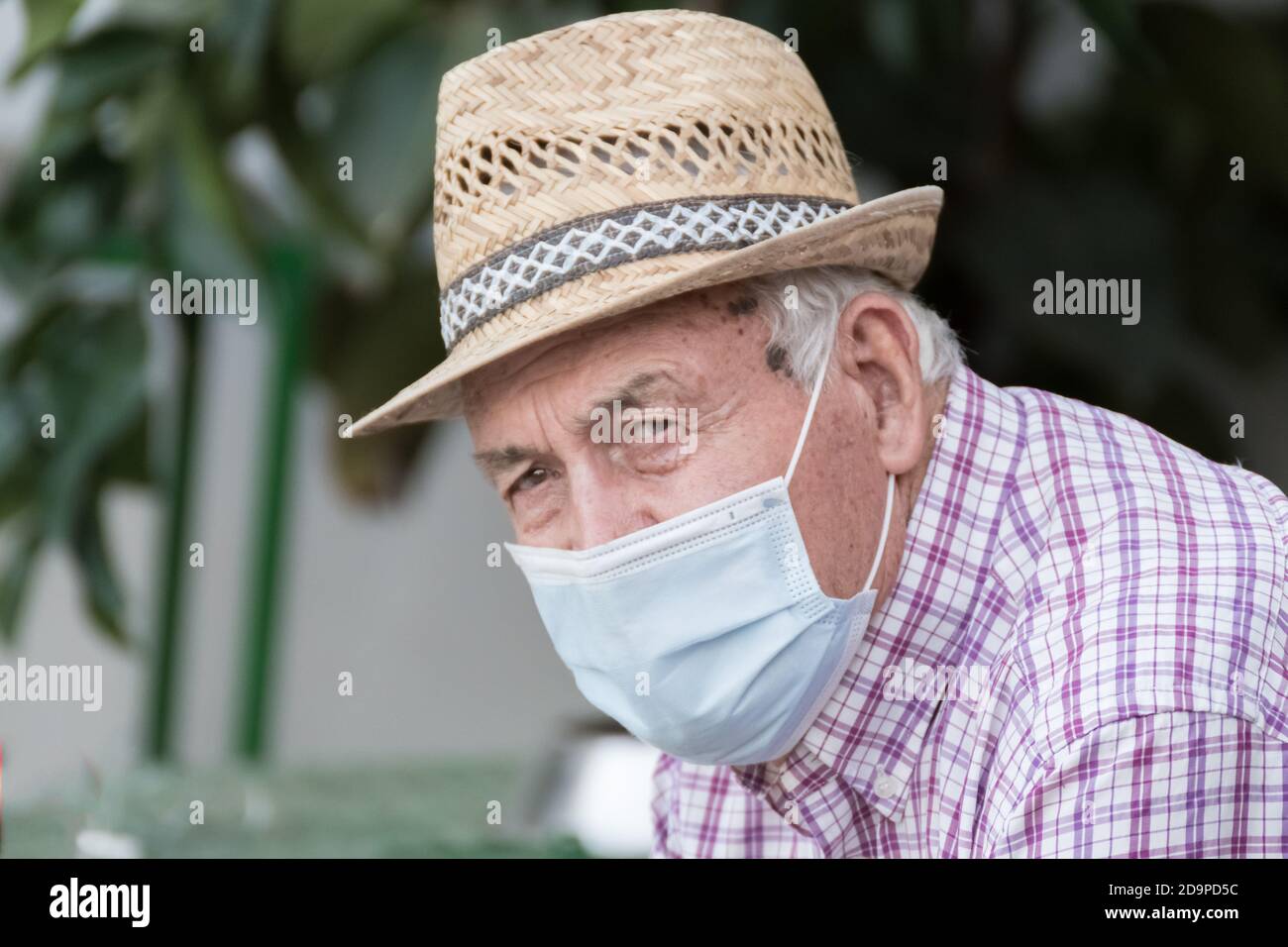 Homme âgé avec chapeau de paille portant un masque de protection du visage en raison de la pandémie mondiale de coronavirus, Covid 19. Banque D'Images