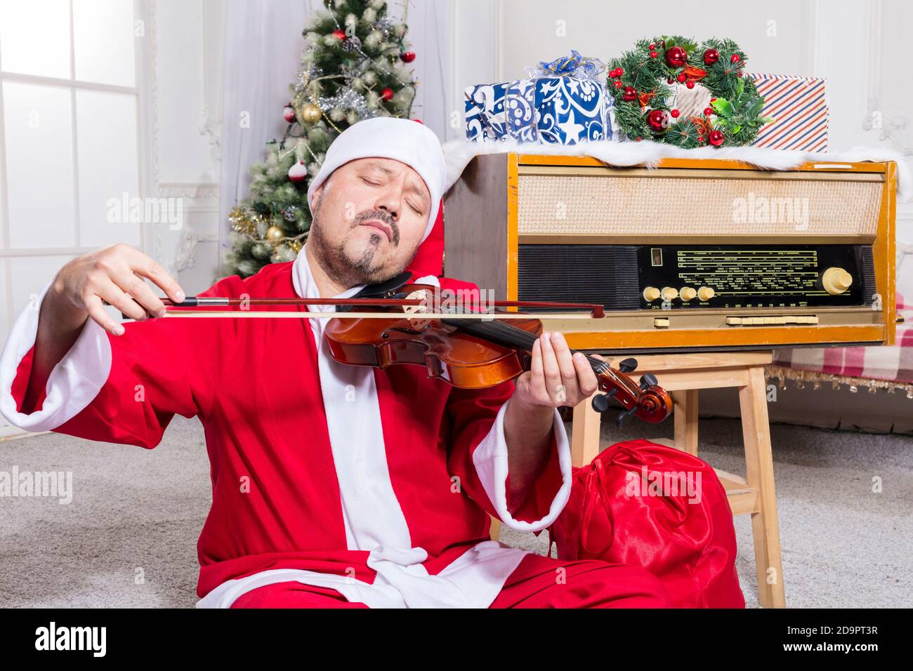 Homme barbu vêtu d'un costume de Père Noël jouant au studio de violons portrait Banque D'Images