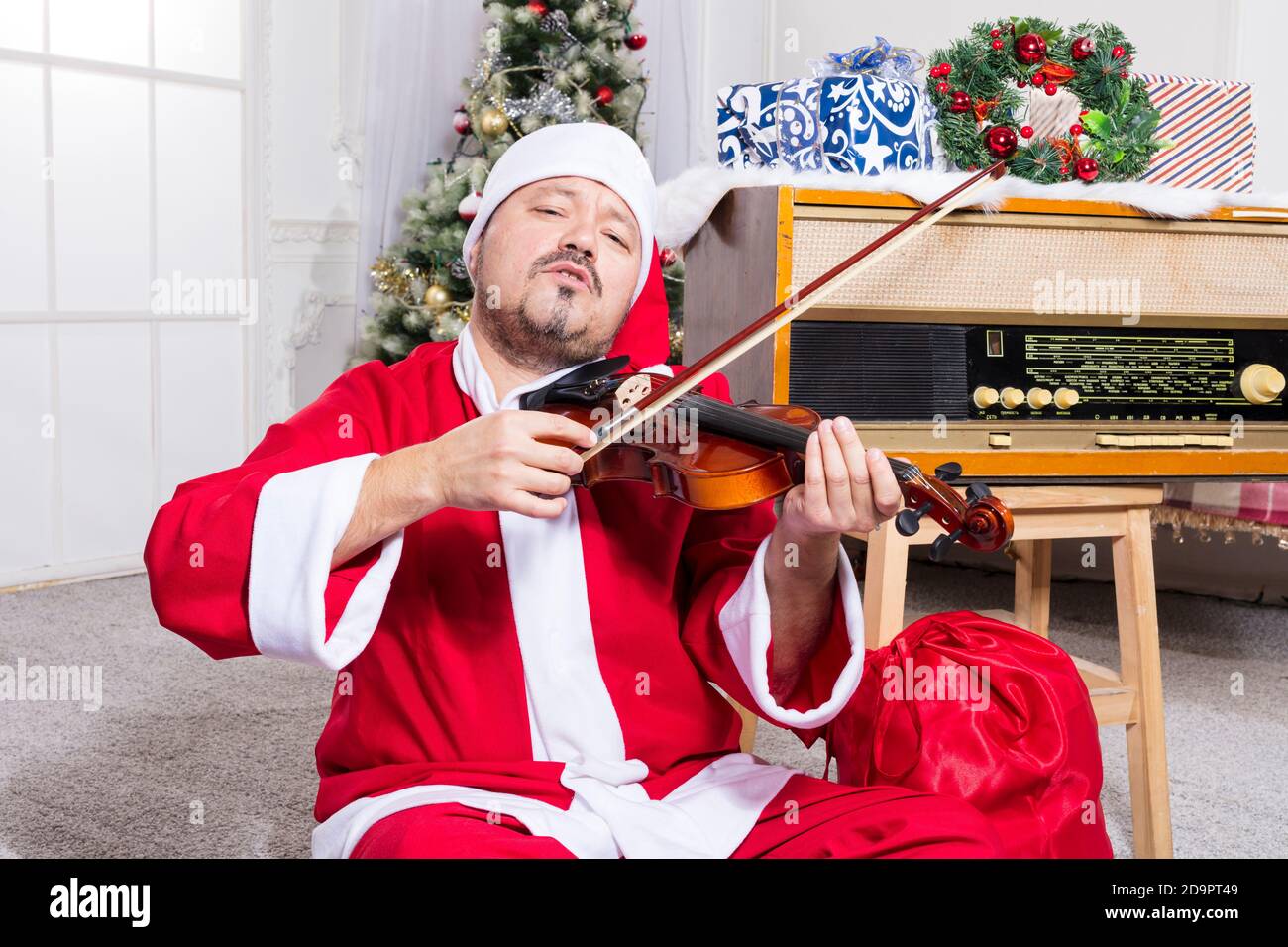 Homme barbu vêtu d'un costume de Père Noël jouant au studio de violons portrait Banque D'Images