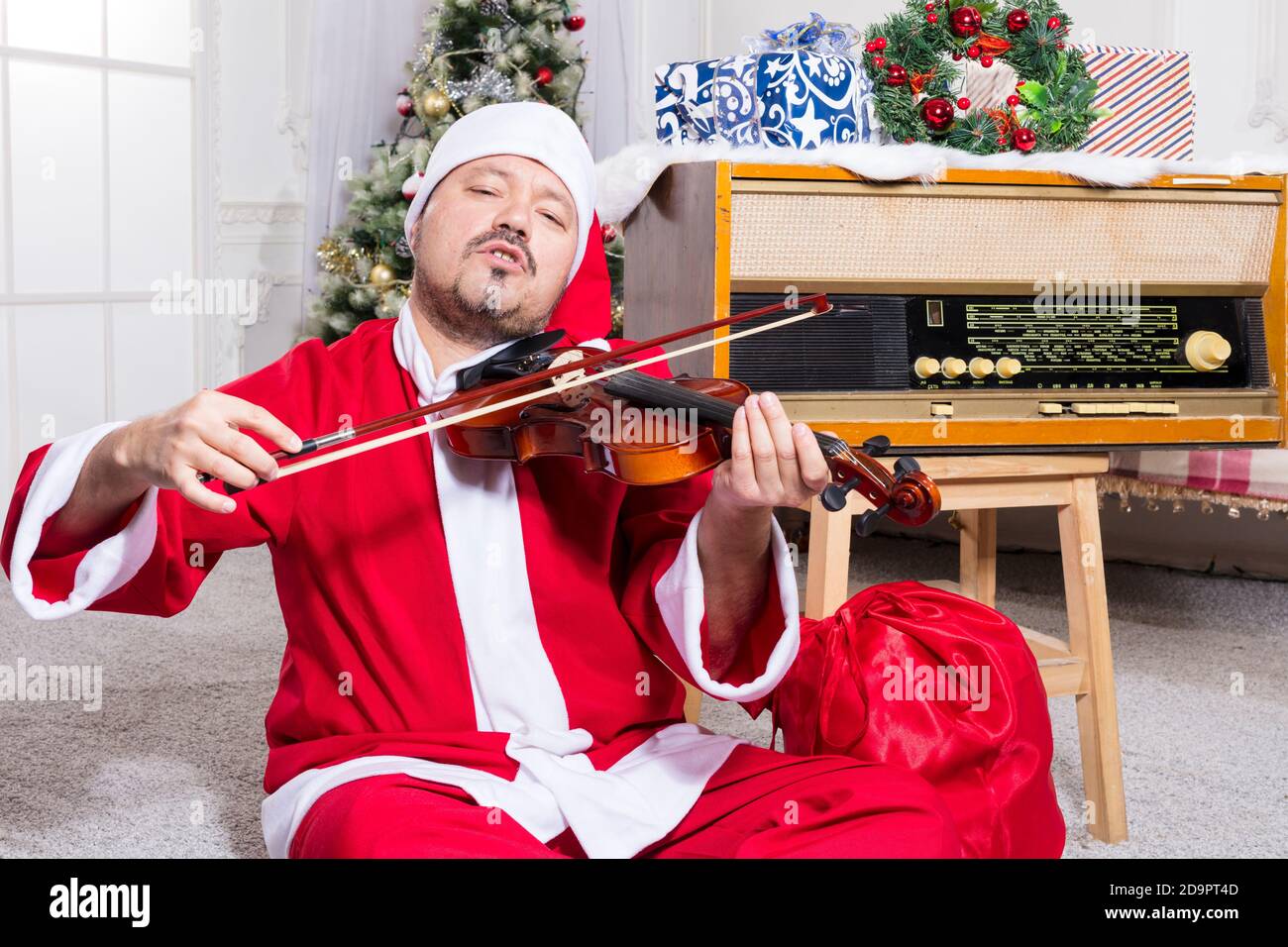 Homme barbu vêtu d'un costume de Père Noël jouant au studio de violons portrait Banque D'Images